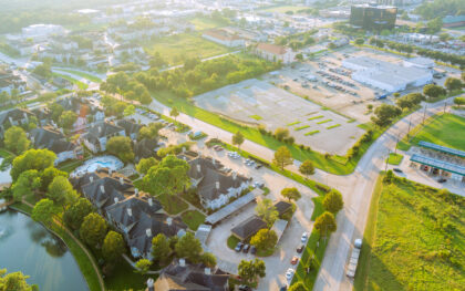 Overview of suburban neighborhood with homes, pool, vacant commercial lots