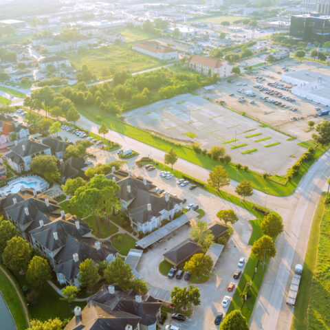 Overview of suburban neighborhood with homes, pool, vacant commercial lots